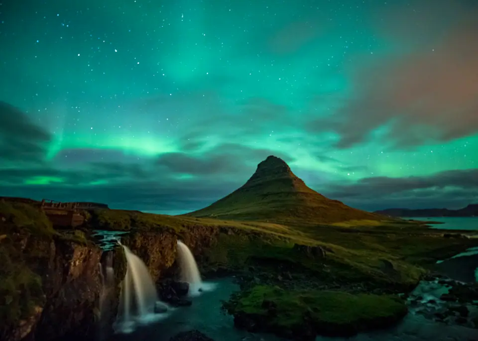 Aurora boreal verde sobre el monte Kirkjufell y la cascada Kirkjufellsfoss, en el oeste de Islandia, en septiembre