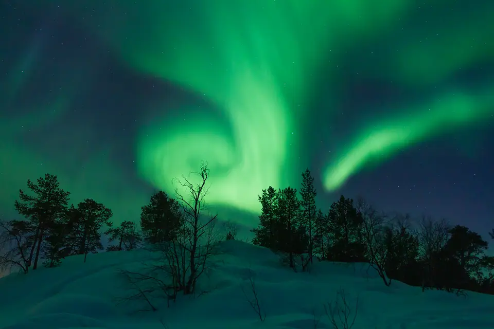 Auroras boreales verdes sobre el paisaje nevado de Laponia, Finlandia