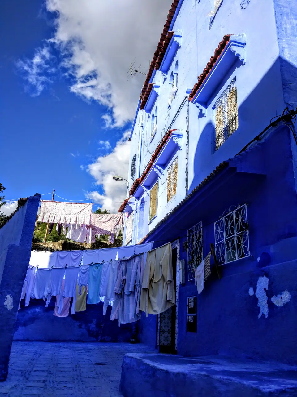 Un callejón de paredes azules con ropa tendida en la medina de Chefchaouen, Marruecos