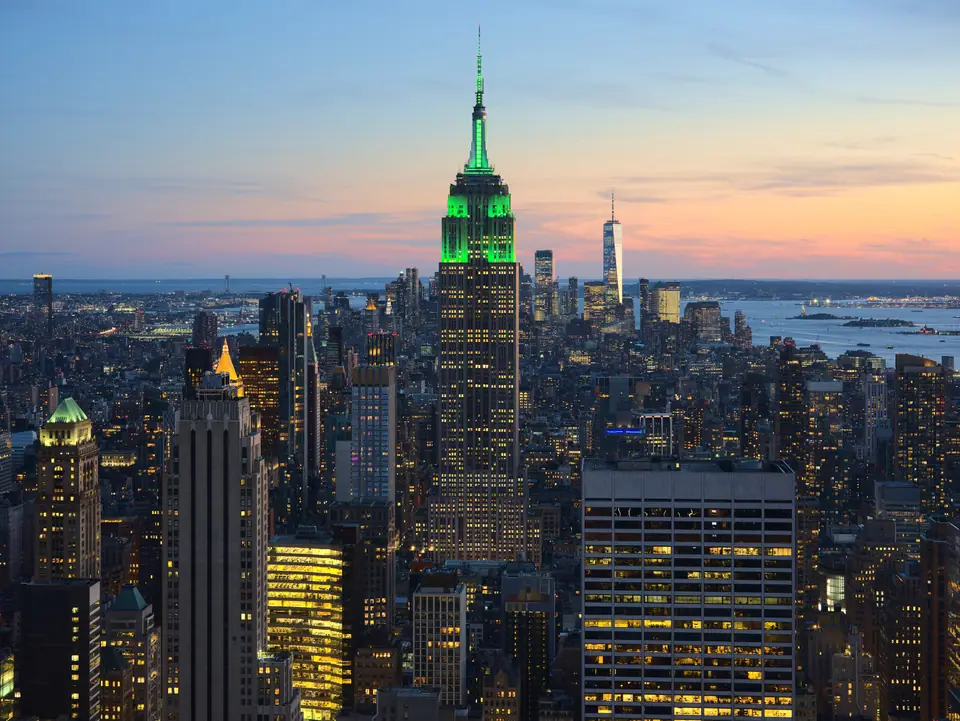 Vista del Empire State Building iluminado y el horizonte de Manhattan al atardecer, desde Rockefeller Center