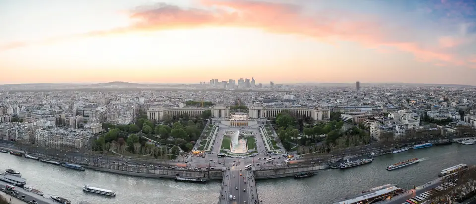 Vista panorámica de París al atardecer desde la Torre Eiffel, con el Sena y los tejados de la ciudad