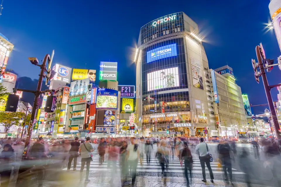 Cruce de Shibuya iluminado de noche, lleno de gente y carteles, Tokio