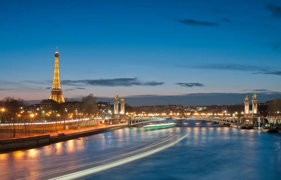 La Torre Eiffel iluminada junto al Sena y el puente Alexandre III, en París, de noche